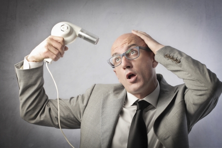 Bald businessman using a hairdryerの写真素材