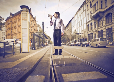 Businessman speaking through a megaphone on a streetの写真素材