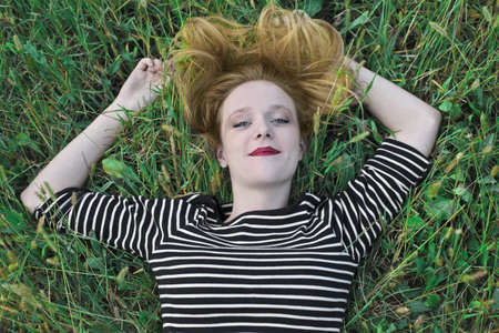 Blonde girl lying on a lawnの写真素材