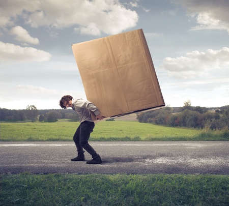 Businessman holding on his shoulders a large boxの写真素材