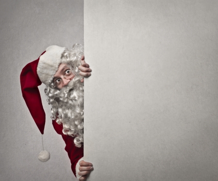 Santa Claus appearing from behind a white wallの写真素材