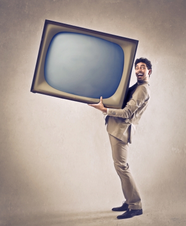 Young businessman holding a big televisionの写真素材