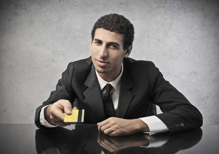businessman sitting at the table with credit card in handの写真素材