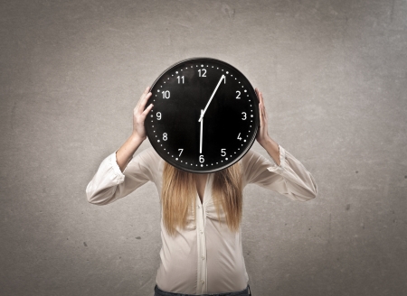 blonde girl with clock in front of face on gray backgroundの写真素材