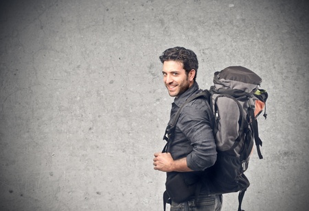 handsome young man with backpack hiking on a gray backgroundの写真素材
