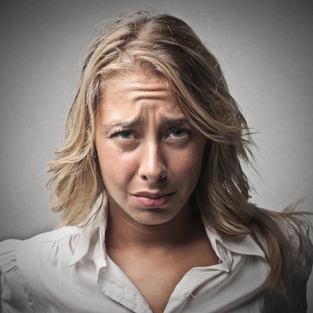 portrait of sad blonde woman on gray backgroundの写真素材