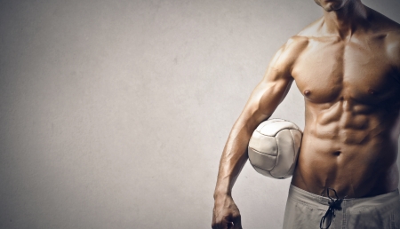 muscular young man with ball on gray backgroundの写真素材