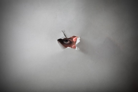 woman spying from a little holeの写真素材