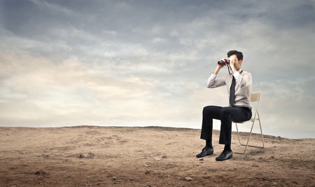 businessman using a binoculars on a chairの写真素材