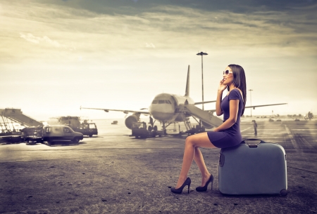business woman sitting on her luggage waiting for a planeの写真素材