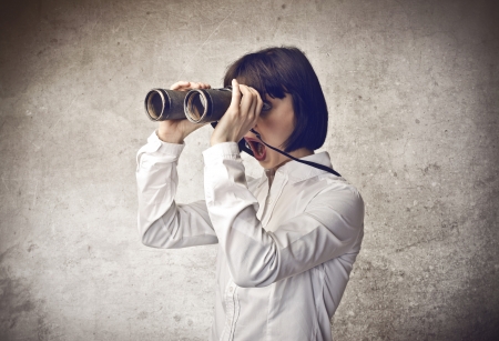 amazed astonished woman looking through a binocularsの写真素材