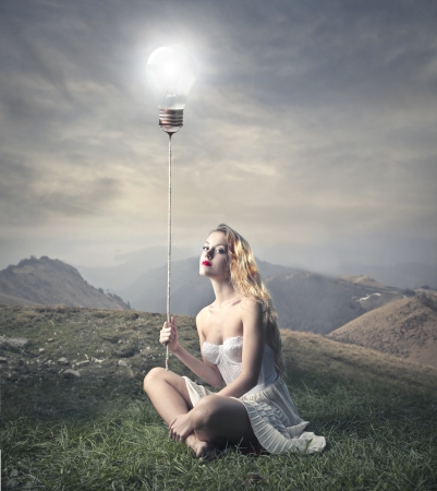 young woman holding a rope with a light bulb on the topの写真素材