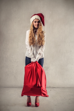 young woman with a Christmas  hat and a red bagの写真素材