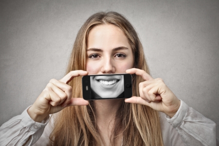 beautiful woman smiling with holding her phoneの写真素材