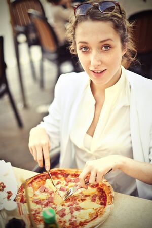 Girl eating a pizza at the restaurantの写真素材