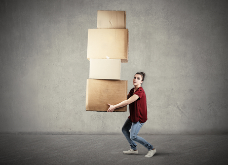 Girl carrying heavy boxesの写真素材