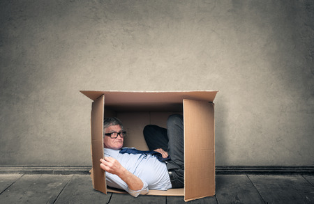 Businessman hiding inside a box