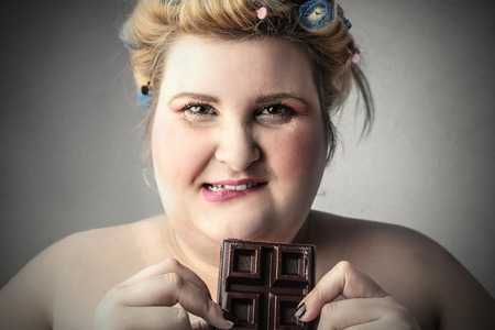 Chubby woman eating chocolateの写真素材