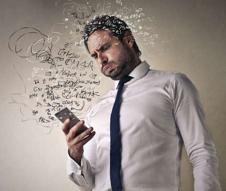 Confused businessman checking his smart phoneの写真素材