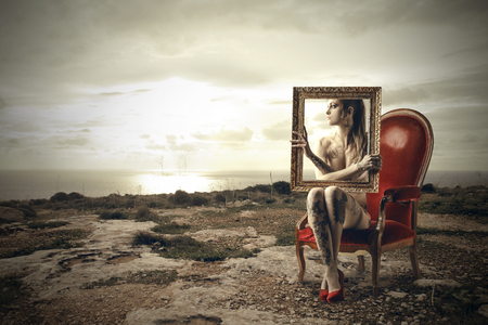Woman sitting on a red chair holding a frameの写真素材