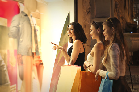 Three girls looking at the window of a shopの写真素材