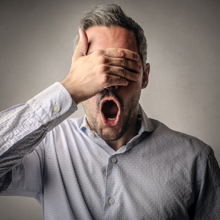 Shocked man covering his eyes with his handの写真素材