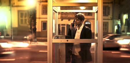 Businessman standing in a phone box doing a callの写真素材