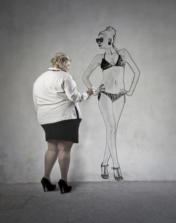Chubby woman drawing a model on the wallの写真素材