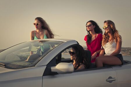 Four girls travelling by carの写真素材