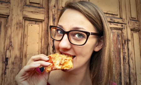 Young girl eating a slice of pizza