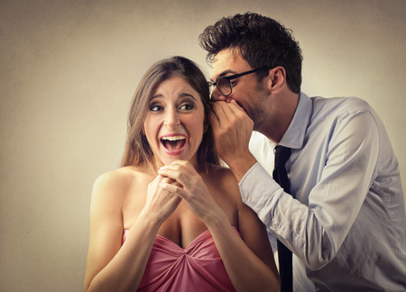 Man whispering into a woman's earの写真素材