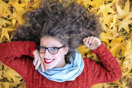 Happy teen lying on yellow autumn leaves