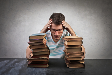 Desperate student with two piles of booksの写真素材