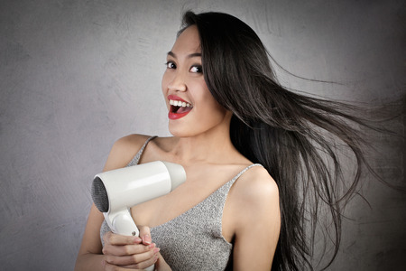 Woman using a hair dryerの写真素材
