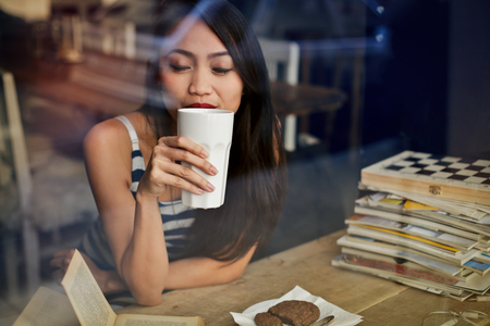 Girl at the cafe drinking a hot drinkの写真素材