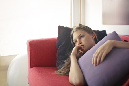 Sad woman lying on the sofaの写真素材