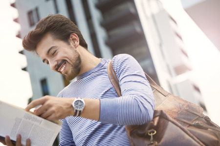 Smiling man reading a bookの写真素材