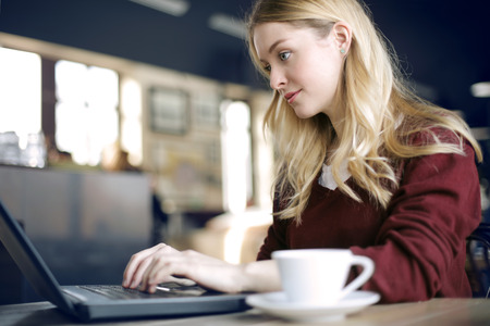 Blonde girl is working next to the coffee