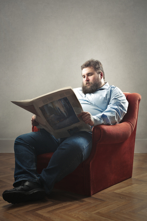 Obese guy is reading the newspaperの写真素材