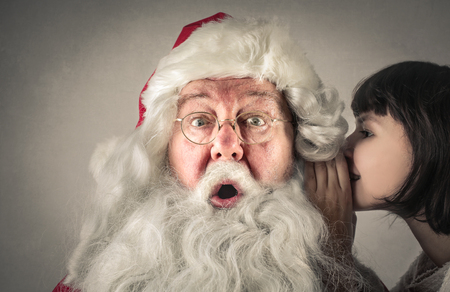 Child is whispering into Santa's earsの写真素材