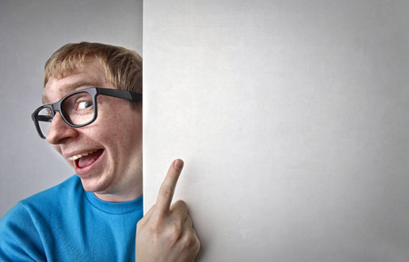 Nerd in glasses pointing at the wallの写真素材