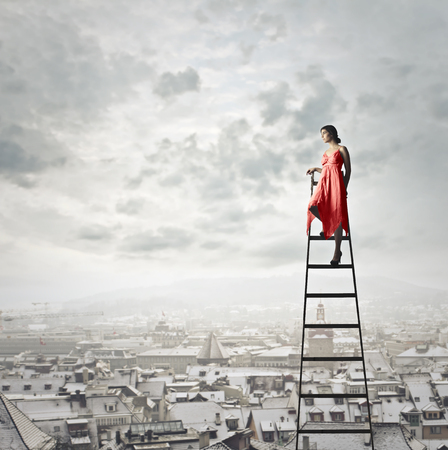 Girl is on the ladder above the cityの写真素材