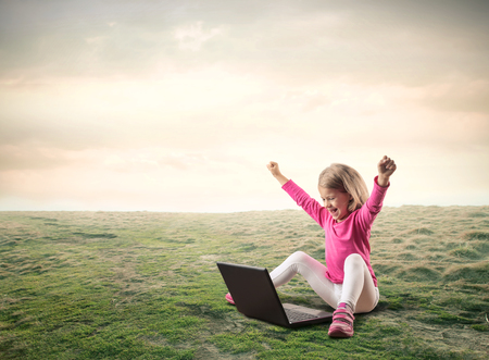 Little girl is playing on the computer outsideの写真素材
