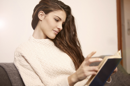A nice girl is reading a book on the sofaの写真素材