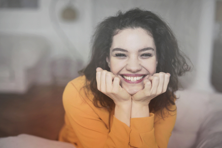 Beautiful girl is smiling in an orange sweaterの写真素材