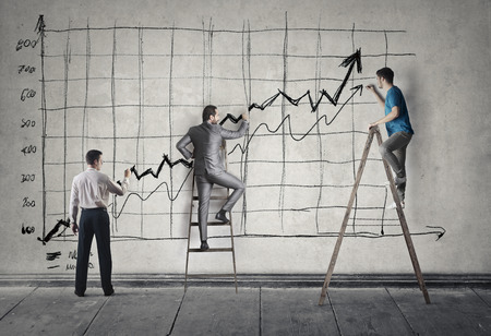 Three people are drawing a giant arrow on the wallの写真素材