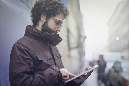 Man is using his tablet on the streetの写真素材