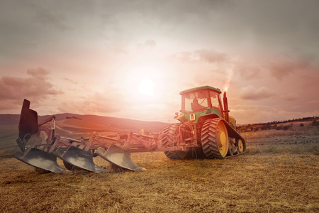 The man is driving a tractor in the sunsetの写真素材