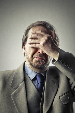 Unhappy businessman is covering his eyesの写真素材