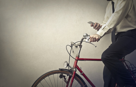 Businessman texting is on the bicycleの写真素材